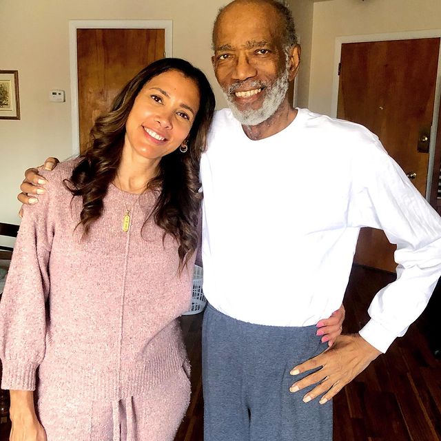 Kristen Baker Bellamy in a light pink tops with her father in a white t-shirt and a blue sweatpants.